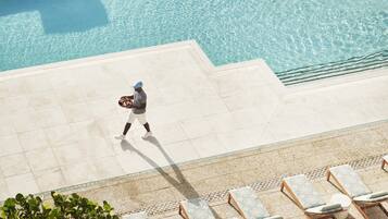 Zona de piscina con sillones de descanso y una persona caminando.