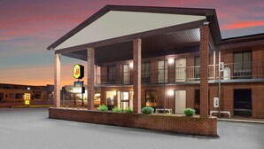 A motel with a covered parking area, a sign for a restaurant, and a brick facade. - Super 8 by Wyndham Sandusky (Sandusky)