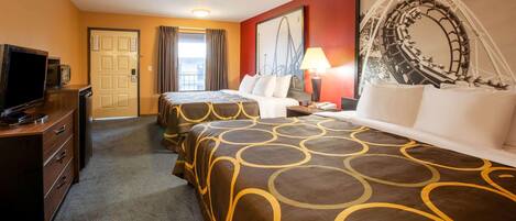 A hotel room with two beds, a desk with a television, a lamp, and a large framed picture on the wall.