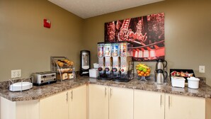 A kitchen area with a granite countertop, a toaster, a coffee maker, and a fruit bowl. - Super 8 by Wyndham Sandusky (Sandusky)