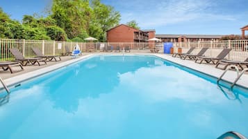 Una piscina al aire libre, sombrillas, sillones reclinables de piscina