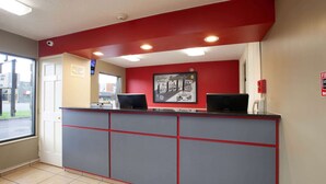A reception area with a red and grey counter, two computers, a fire alarm, and a window with a view of the street. - Super 8 by Wyndham Sandusky (Sandusky)