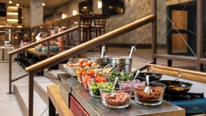 A buffet area with various food stations, including bowls of salad, meat, and other dishes. - The Westin Edmonton (Edmonton)