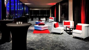 A modern lounge area with a round table, white sofas with red cushions, and a red rug. - The Westin Edmonton (Edmonton)