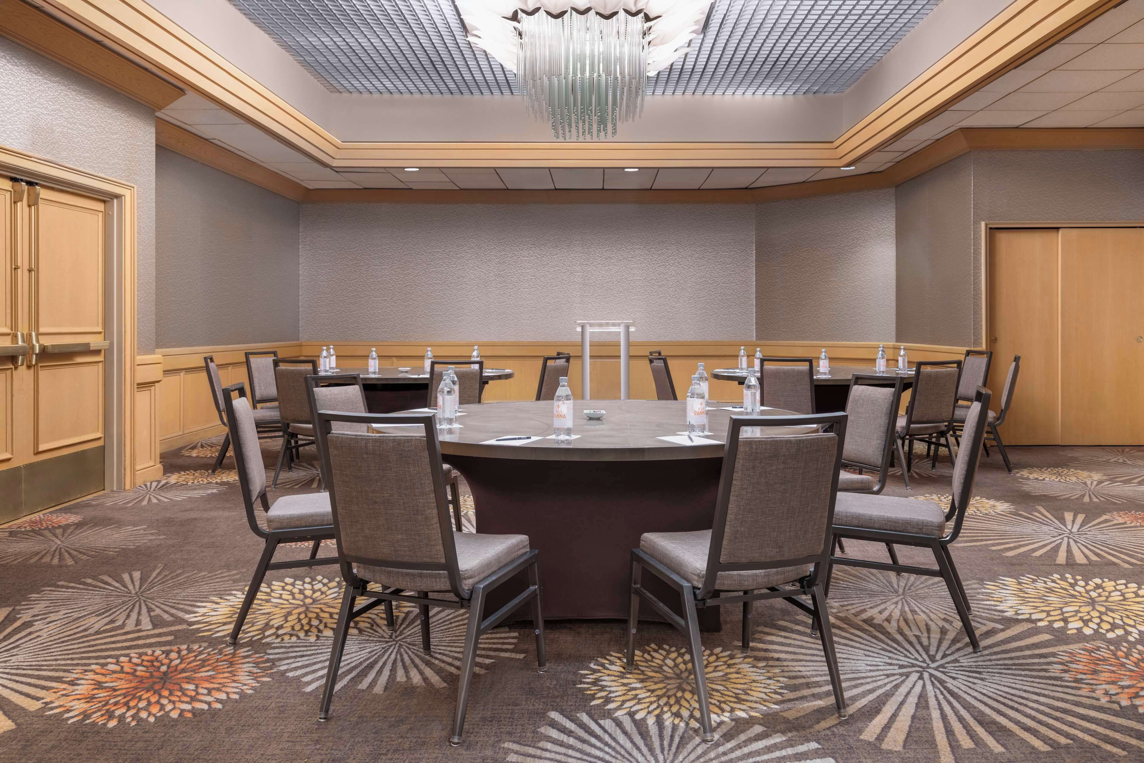 A conference room with a large oval table, six chairs, and a chandelier.