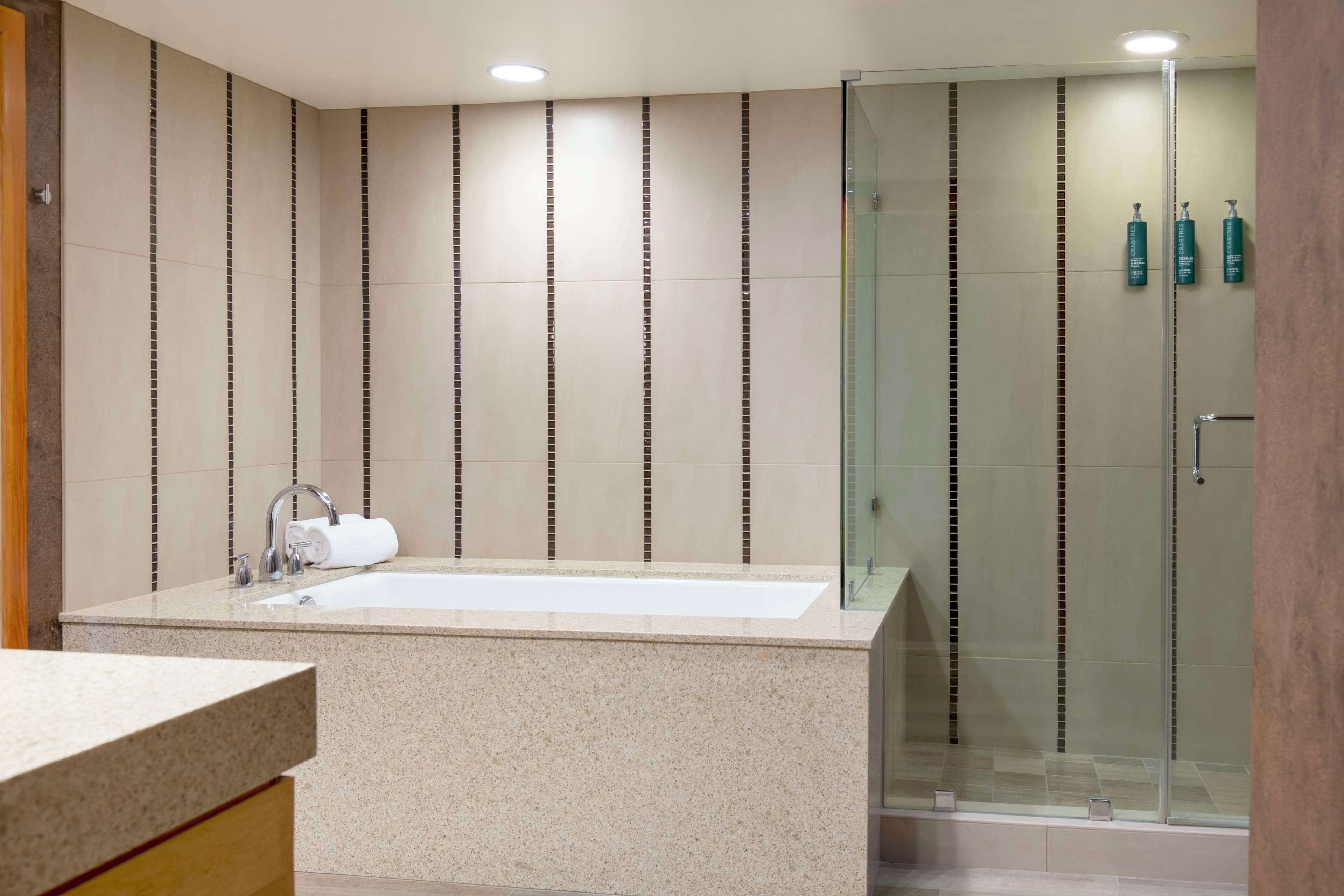 A modern bathroom with a large bathtub, a glass-enclosed shower, and a sink with a towel.