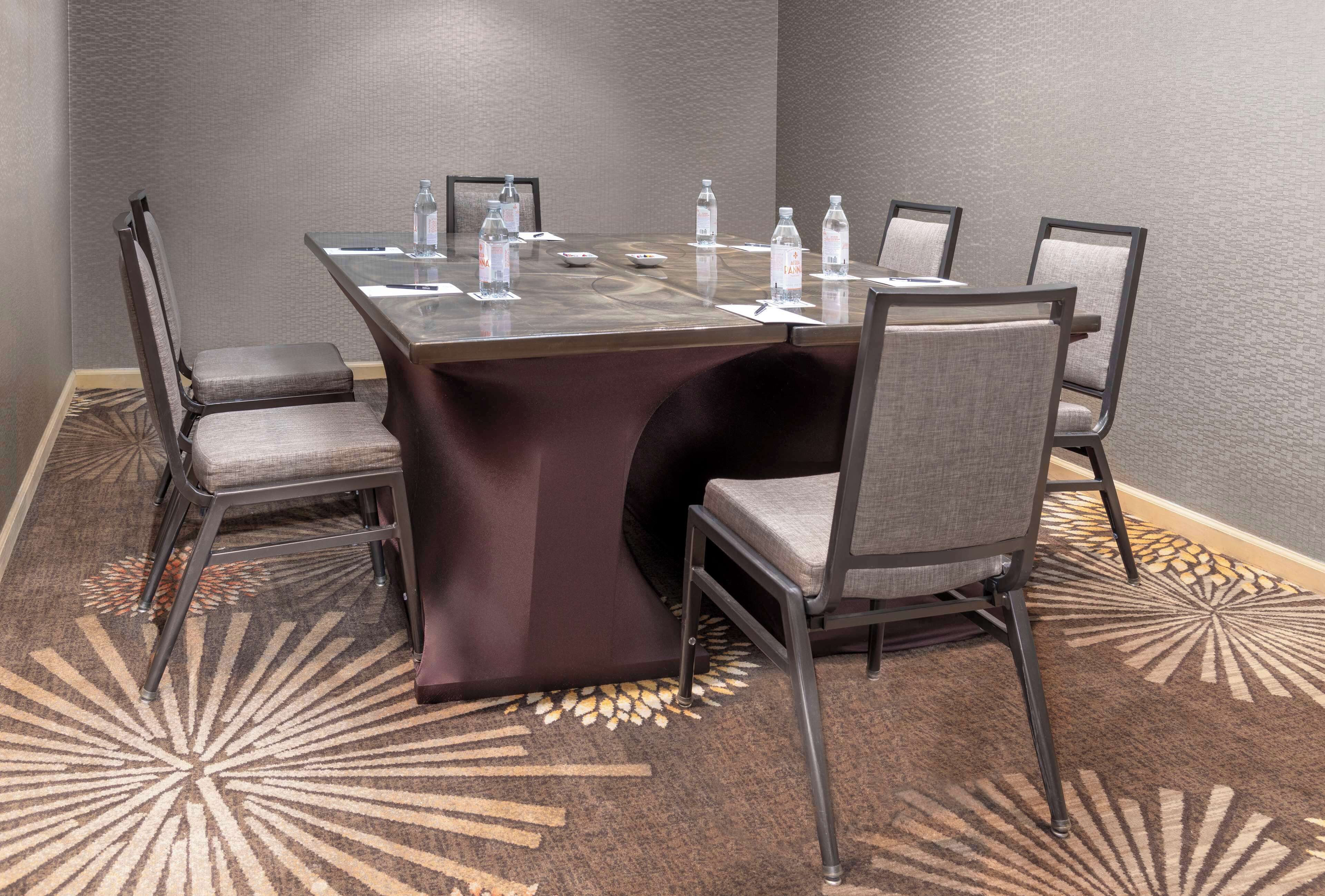 A conference room with a glass table, six chairs, and water bottles on the table.