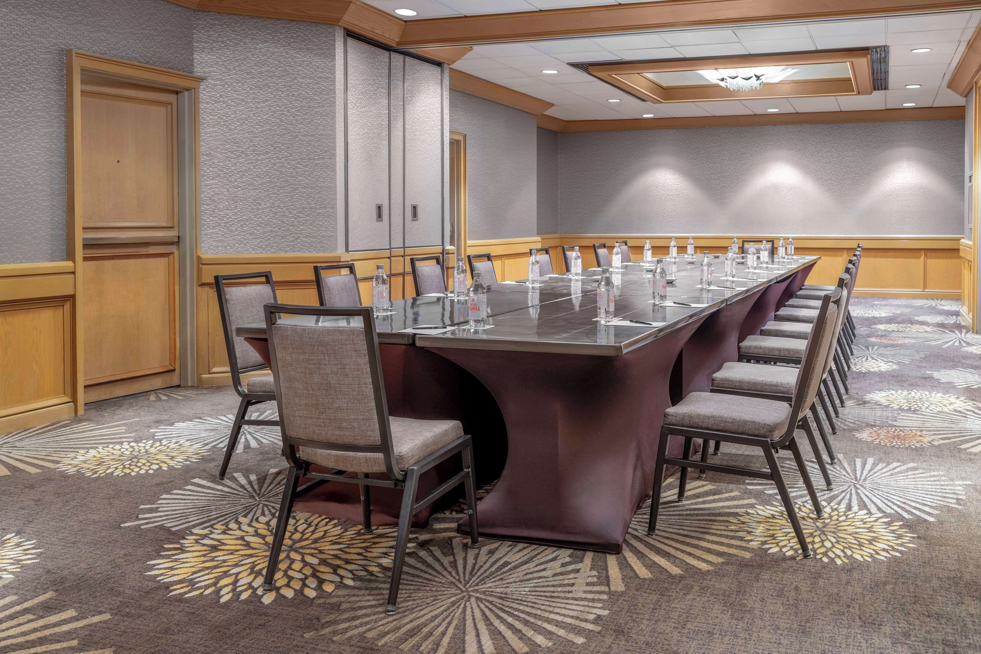 A conference room with a long table, chairs, and a carpeted floor.
