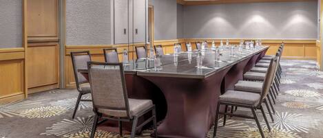 A conference room with a long table, chairs, and a carpeted floor.