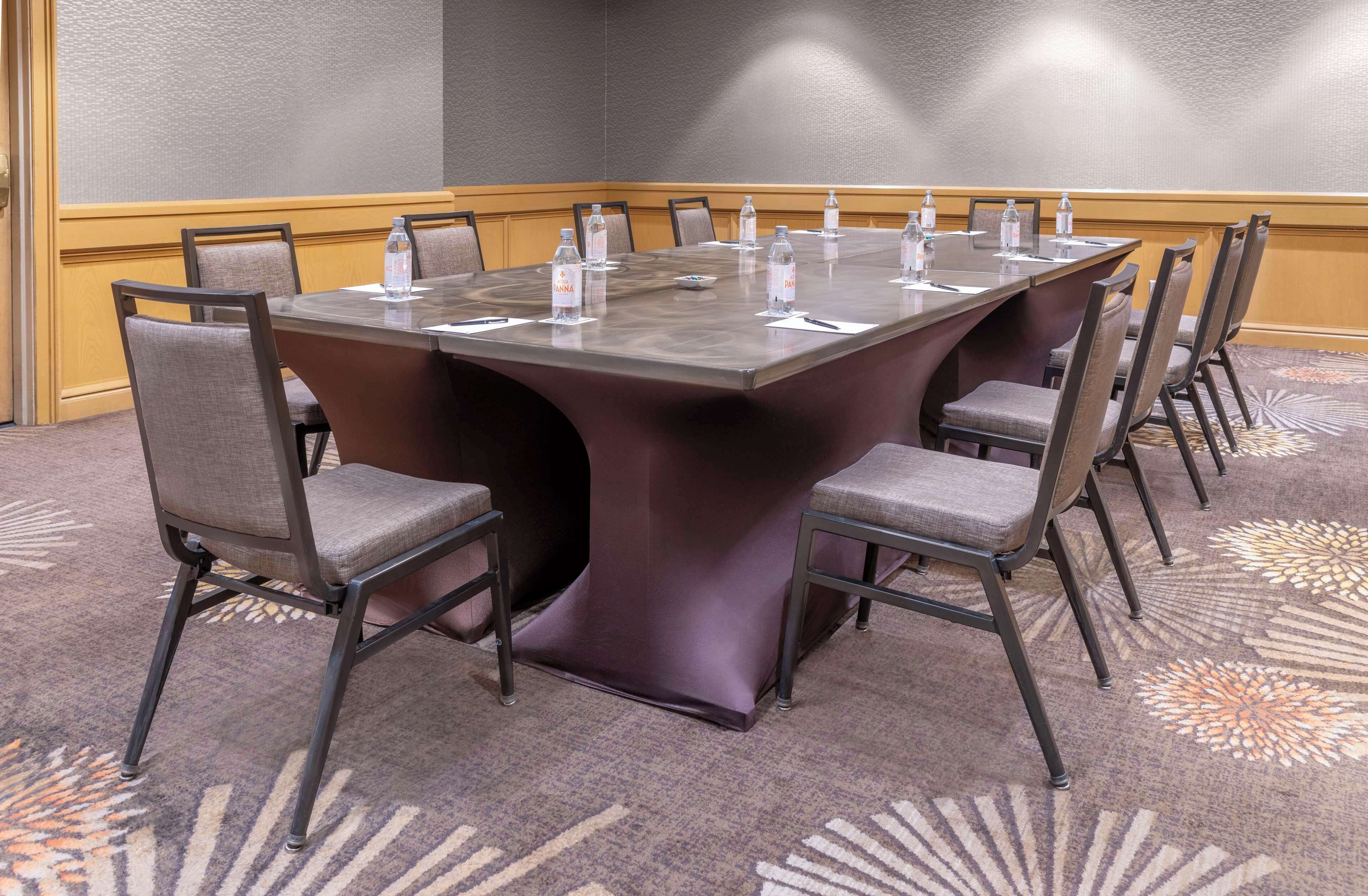 A conference room with a large rectangular table, eight chairs, and water bottles on the table.