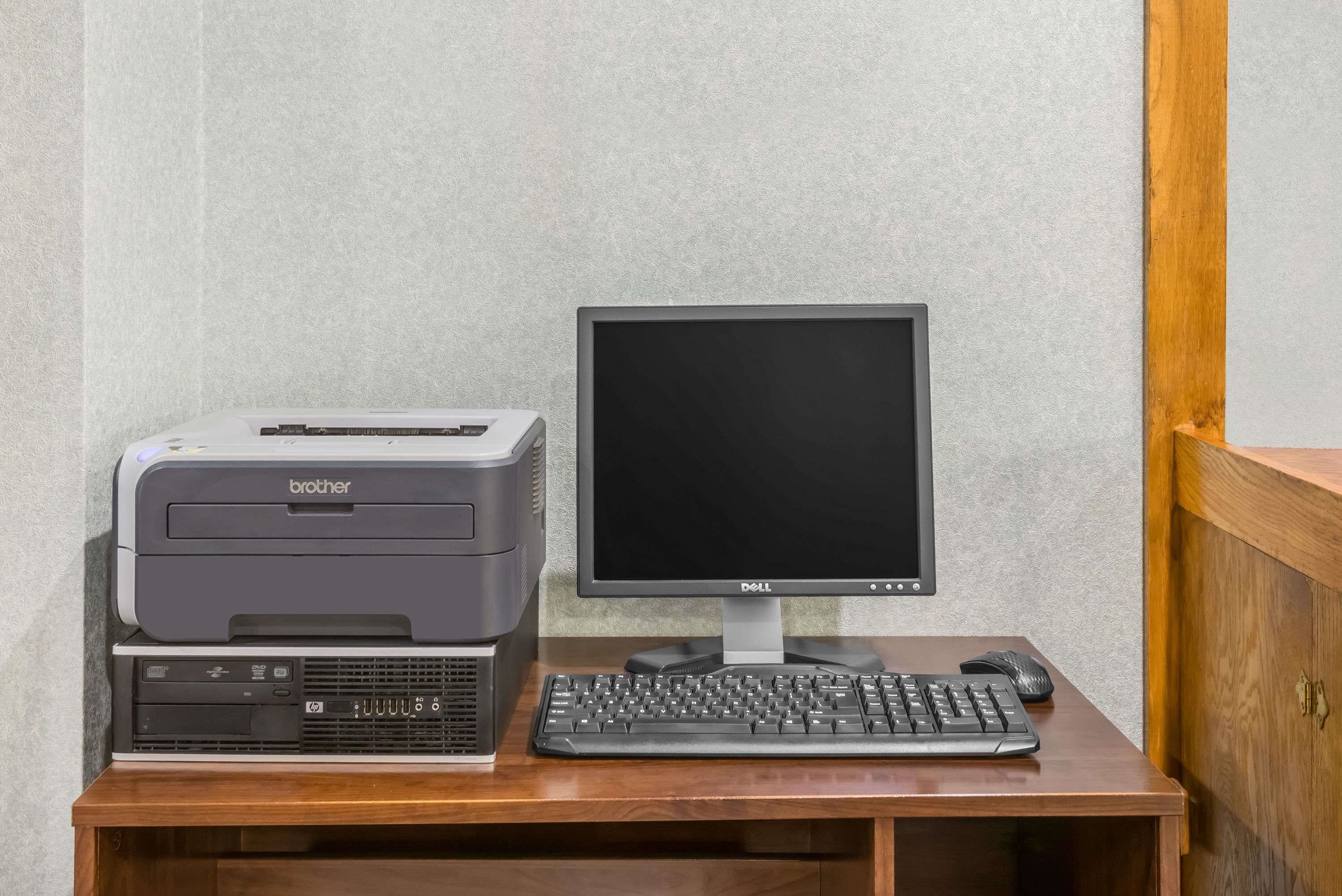 A desktop computer with a Brother printer, a Dell monitor, and a keyboard on a wooden desk.