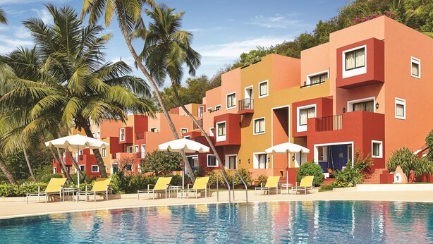 A hotel with a swimming pool, yellow sun loungers, and red buildings. - Taj Cidade de Goa Heritage, Goa (Panaji)