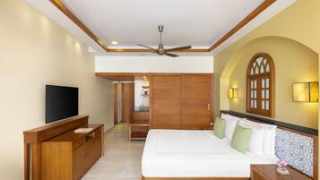 Un dormitorio con cama, muebles de madera, ventilador de techo y televisor.