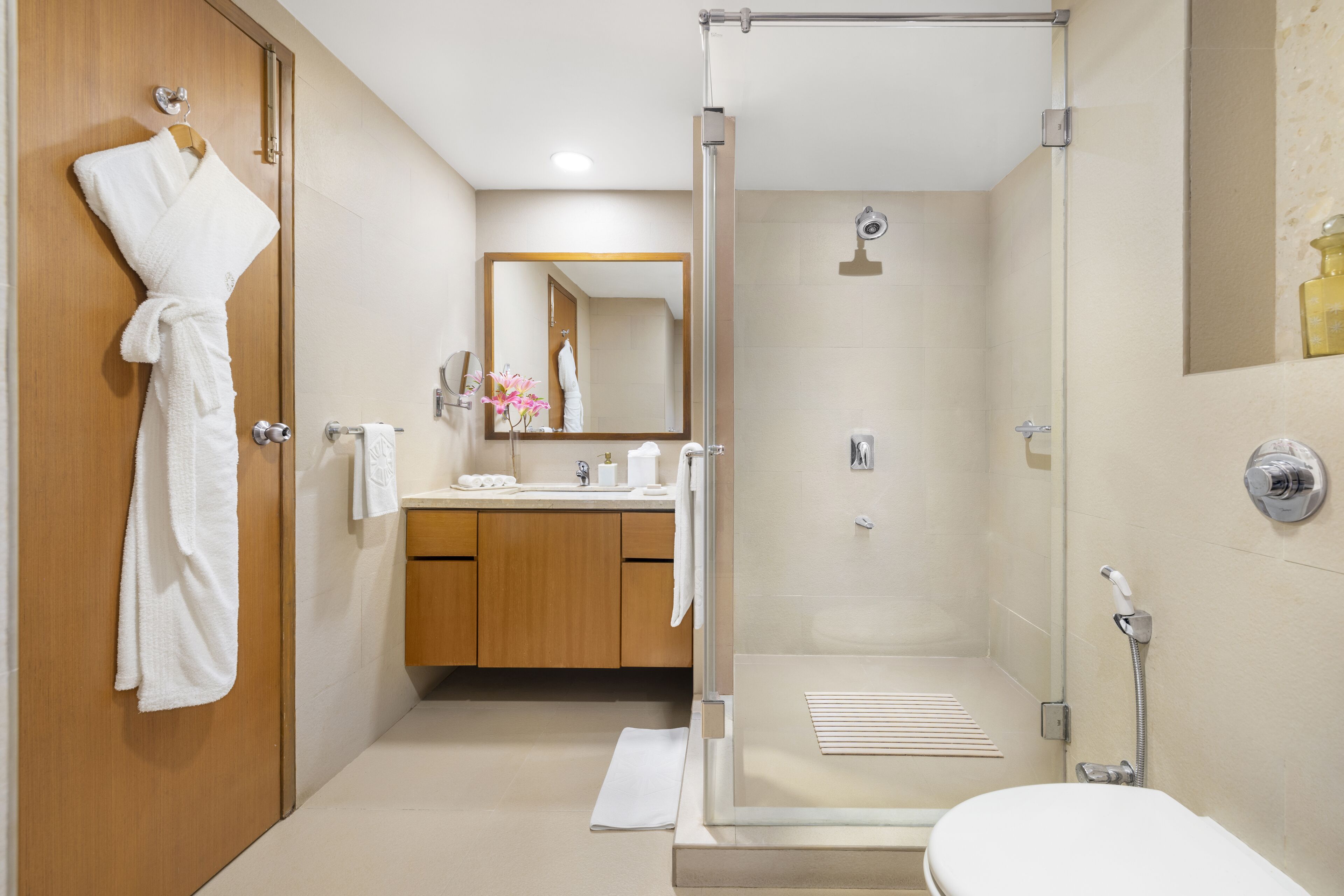 A modern bathroom with a glass-enclosed shower, a wooden vanity, and a white bathtub.