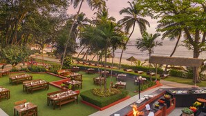 A restaurant with outdoor seating overlooking a beach, a chef preparing food, and a buffet area. - Taj Cidade de Goa Heritage, Goa (Panaji)