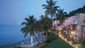 A beachfront hotel with palm trees, a beach, and boats. - Taj Cidade de Goa Heritage, Goa (Panaji)