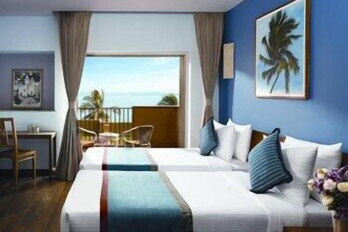 Une chambre d’hôtel avec deux lits, un balcon donnant sur un beau paysage et un tableau accroché au mur.