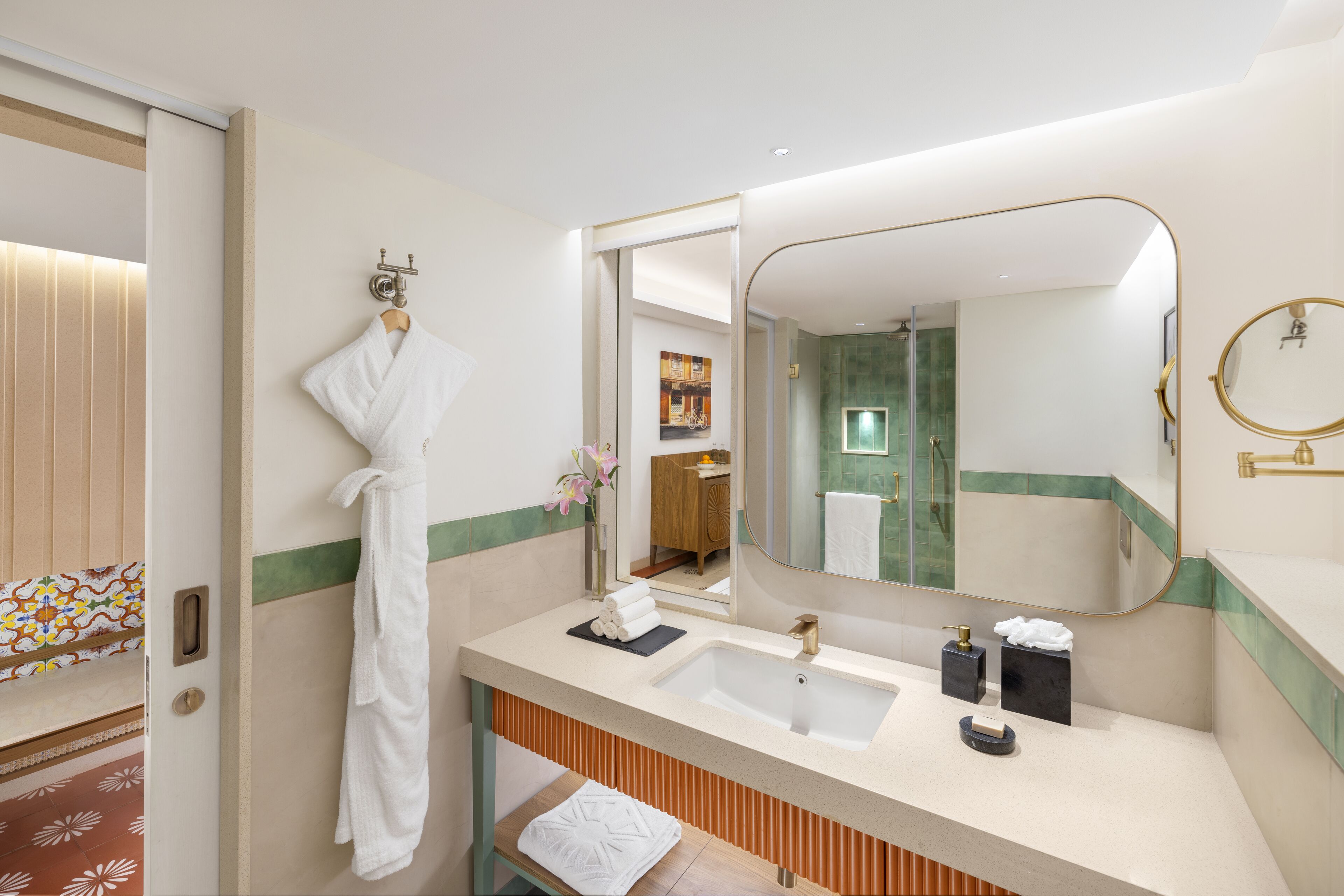 A modern bathroom with a large mirror, a sink, and a robe hanging on the wall.