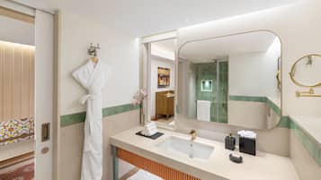 Un baño moderno con un espejo grande, un lavamanos y una bata colgada en la pared.