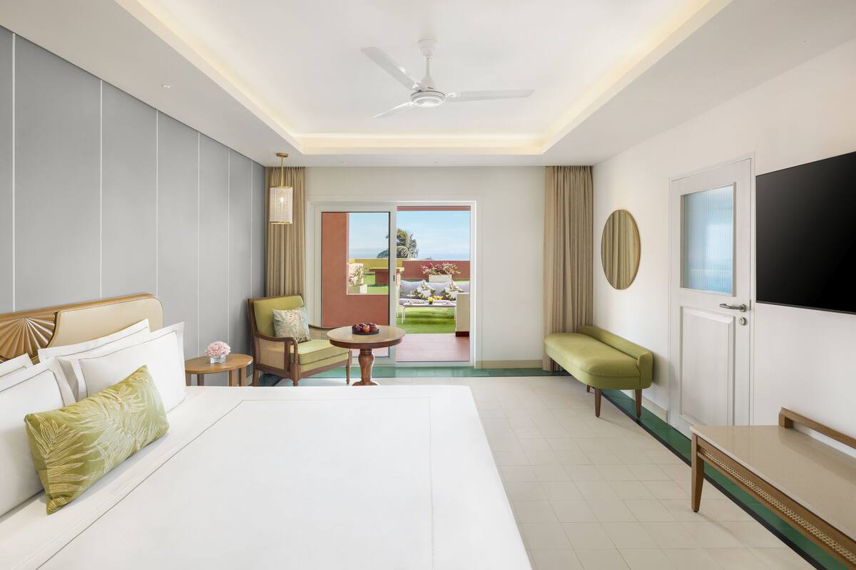 Une chambre d’hôtel dotée d’un grand lit, d’un coin salon avec une table et des chaises, d’une télévision et d’un balcon avec vue.