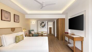A hotel room with a large bed, a desk, a television, and a dining area.