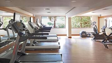 Een sportschool met loopbanden, elliptische trainers en een hometrainer.
