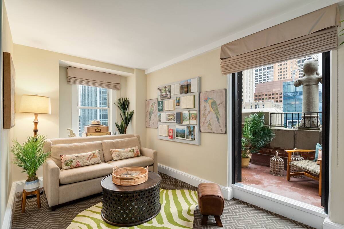 A living room with a sofa, coffee table, and a view of the city through large windows.