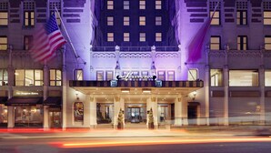 A hotel with a classic facade, a prominent entrance, and an American flag.