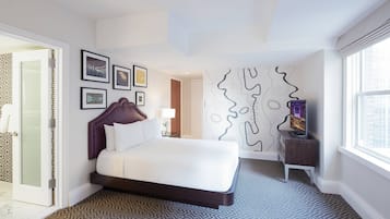 A modern hotel room with a large bed, a TV, and a unique wall art piece.