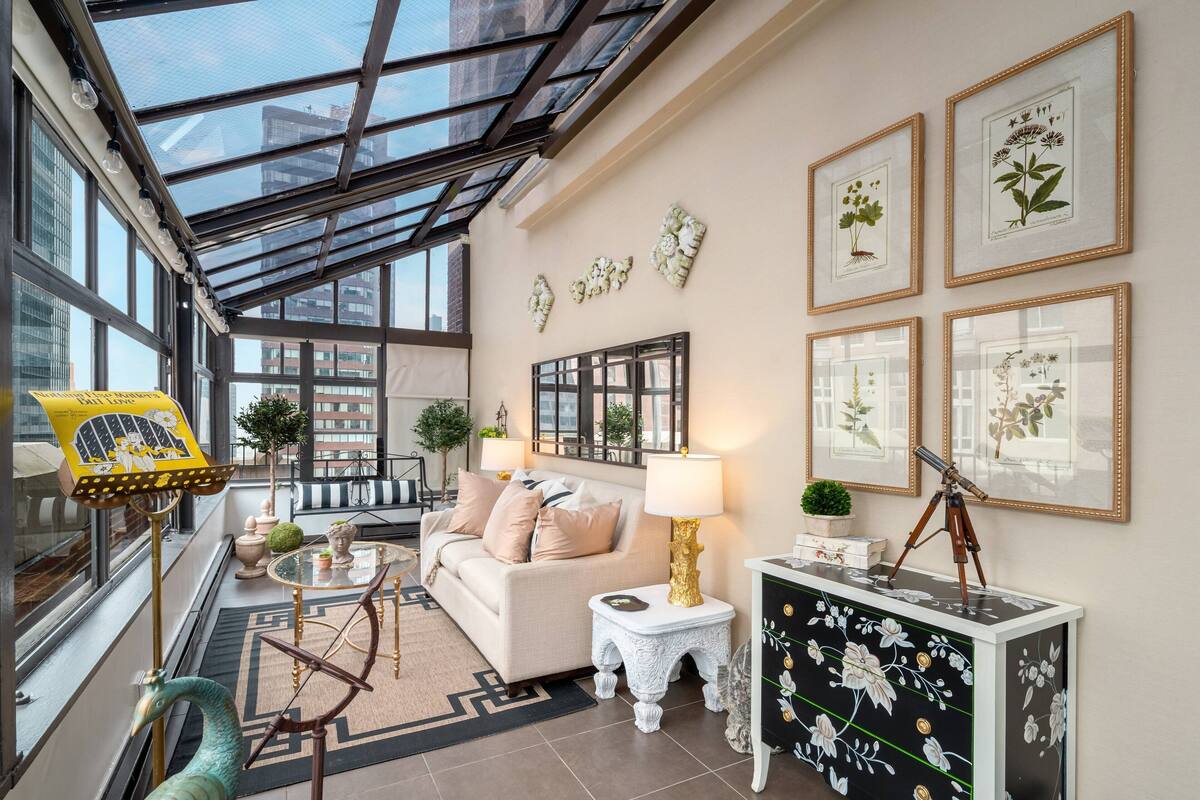 A modern living room with a glass ceiling, a sofa, a coffee table, and framed botanical prints on the wall.