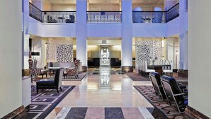 A spacious lobby with a central seating area, a high ceiling with skylights, and a reflective floor.