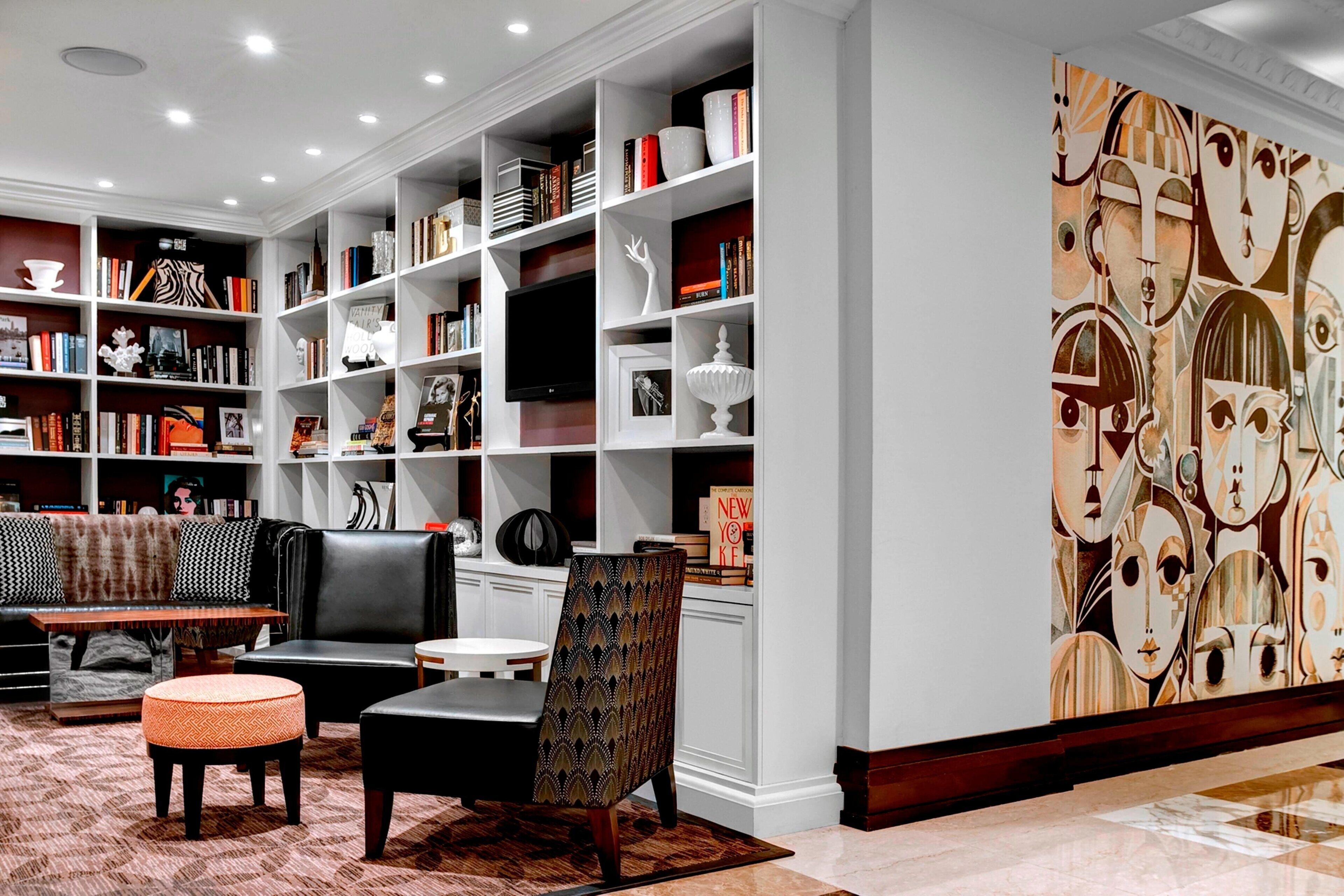 A modern living room with a large bookshelf, a sofa, a coffee table, and a patterned armchair.