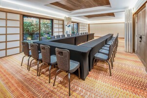 Un salón de conferencias con una mesa larga, sillas y una alfombra estampada.