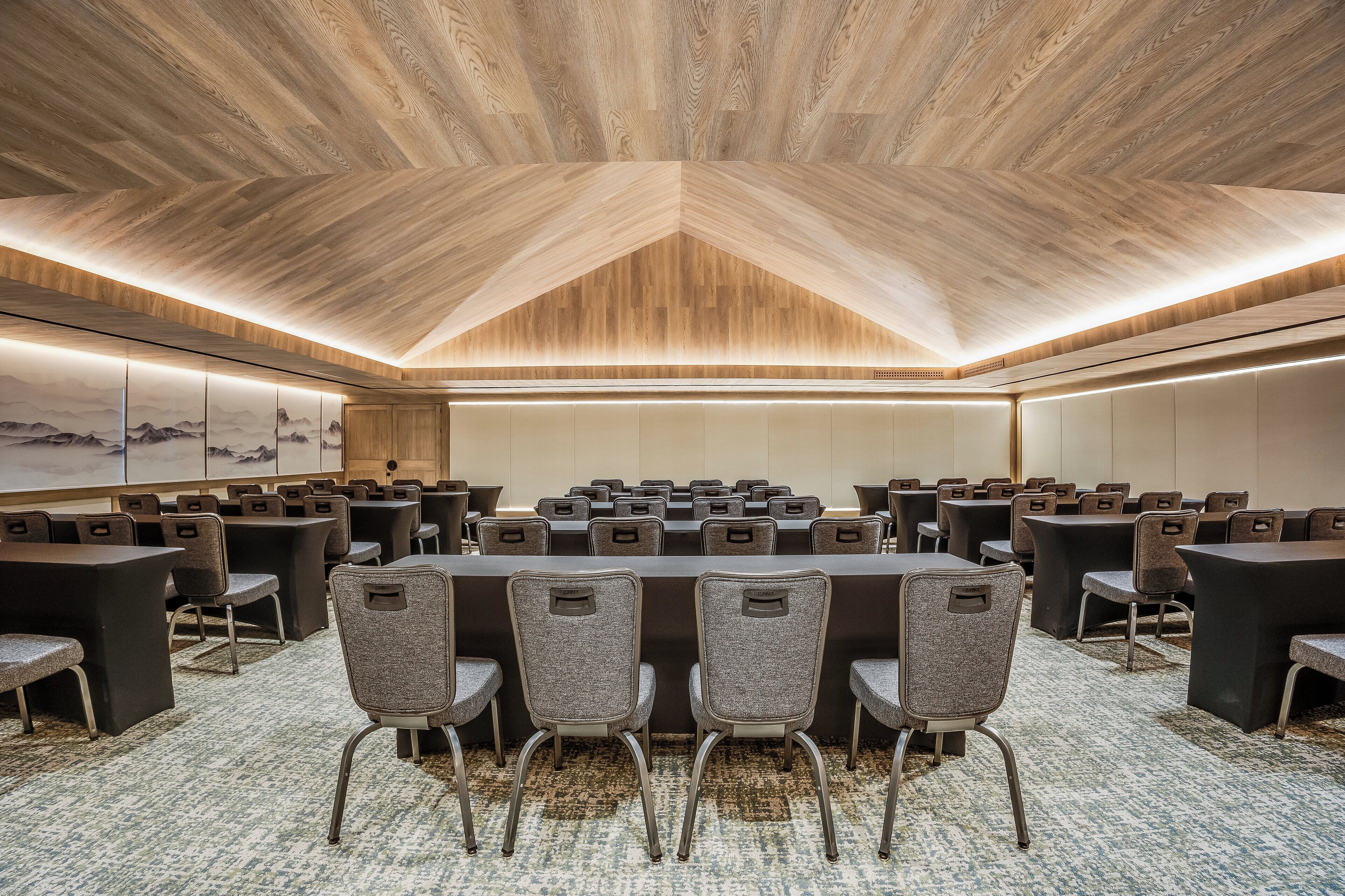 Un salón de conferencias con techo de madera, varias mesas y sillas dispuestas para reuniones.