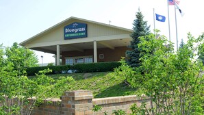 A Bluegrass Extended Stay hotel with a brick facade, a covered entrance, and American flags.