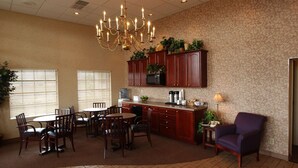 A spacious kitchen with a dining area, featuring a chandelier, wooden cabinets, and a purple armchair.