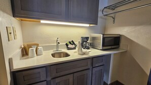A compact kitchen with a stainless steel sink, a coffee maker, and a microwave.