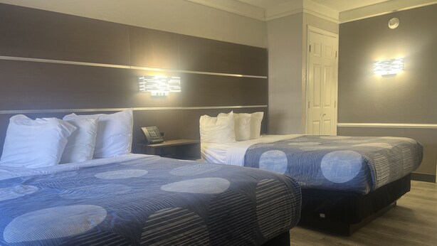 Habitación de hotel con dos camas, una mesita de noche con teléfono y una lámpara fijada a la pared.