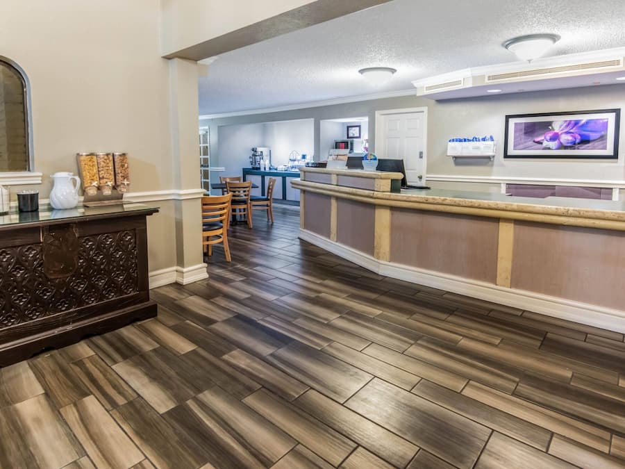A hotel lobby with a reception desk, wooden flooring, and a coffee station.