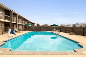 A swimming pool with lounge chairs and umbrellas, surrounded by a building with balconies. - La Quinta Inn By Wyndham IH-10 West San Antonio TX (San Antonio)