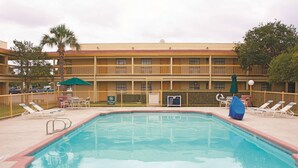 Zona de piscina con tumbonas, sombrillas y un cartel que prohíbe los saltos.
