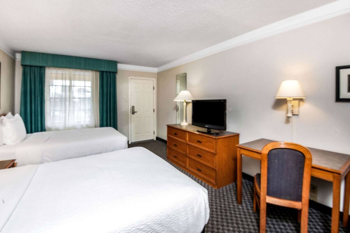 Une chambre d’hôtel avec deux lits, un bureau, une télévision et une chaise.