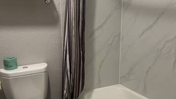 Une salle de bain équipée de toilettes, d’une baignoire et d’un rideau de douche.