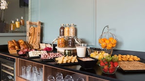 Un bufé de desayuno con diferentes opciones de comida, como pan, bollería, frutas y bebidas.