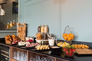 Un bufé de desayuno con diferentes opciones de comida, como pan, bollería, frutas y bebidas.