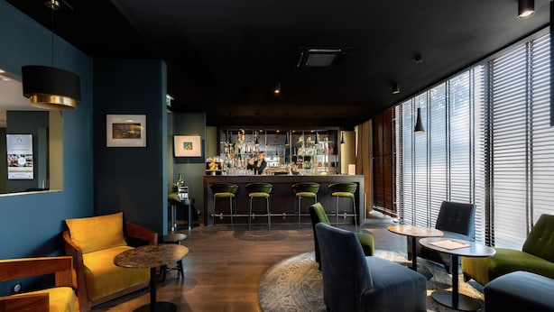 Zona de bar con mostrador, taburetes y área de estar con sofás y mesas.