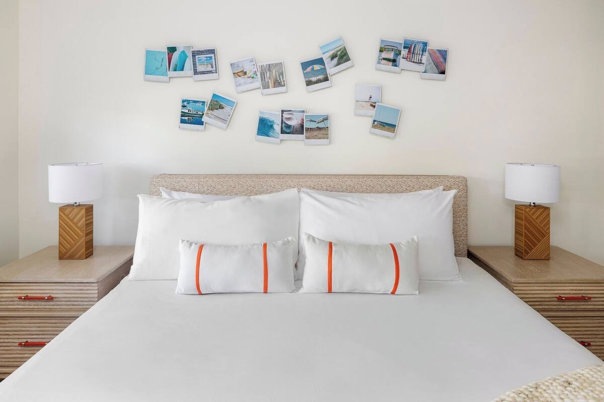 A hotel room with a large bed, two bedside tables with lamps, and a wall decorated with photos.