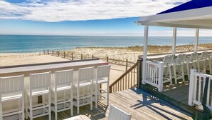 A beachside deck with white chairs and a covered area overlooking the ocean. - Blue Water Resort (South Yarmouth)