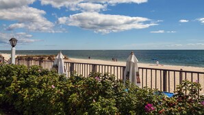 A beach with a wooden fence, a lamp post, and a clear view of the ocean. - Blue Water Resort (South Yarmouth)