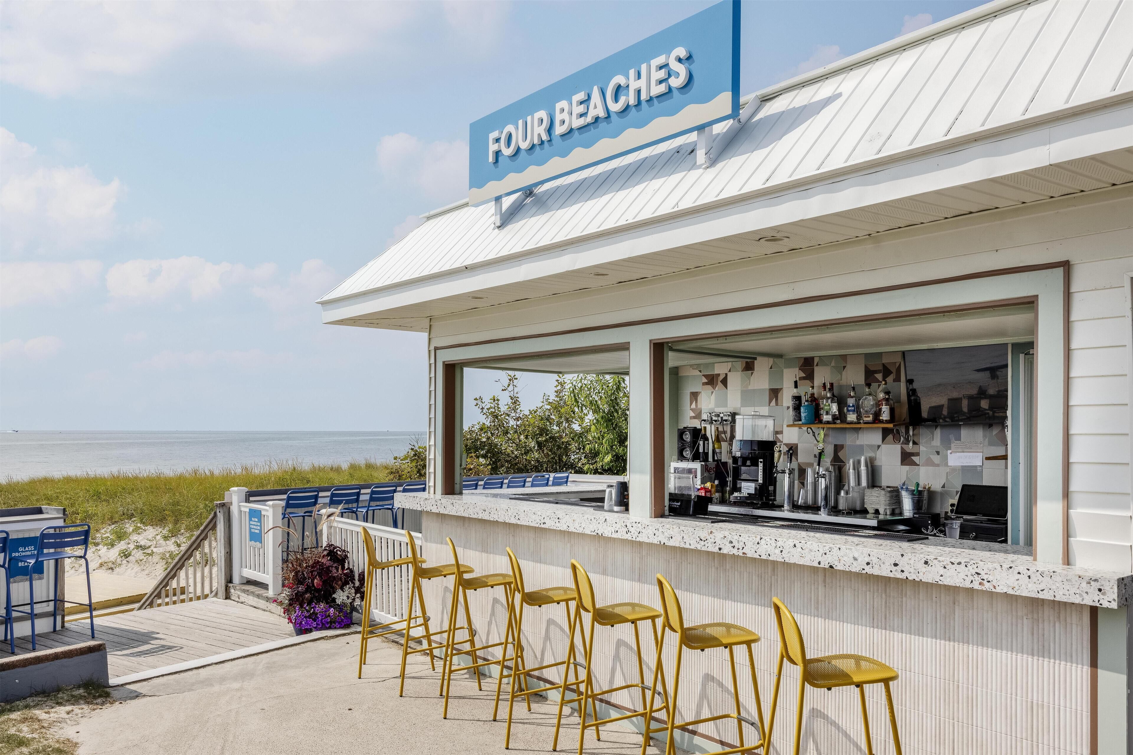Un bar situé en bord de mer, appelé « Four Beaches », avec une terrasse et une vue sur l’océan.